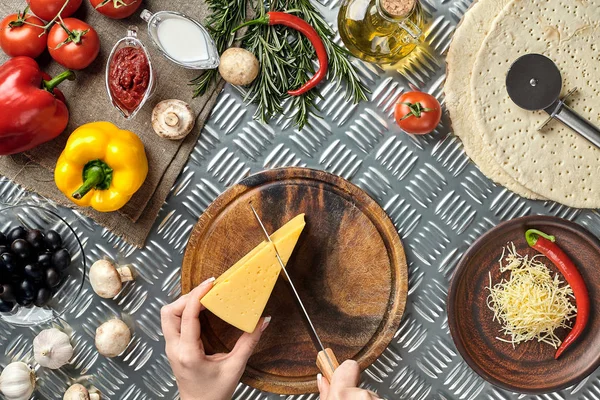 Részleges kilátás nyílik a nő vágás sajtot, házi készítésű olasz pizza főzés közben — Stock Fotó