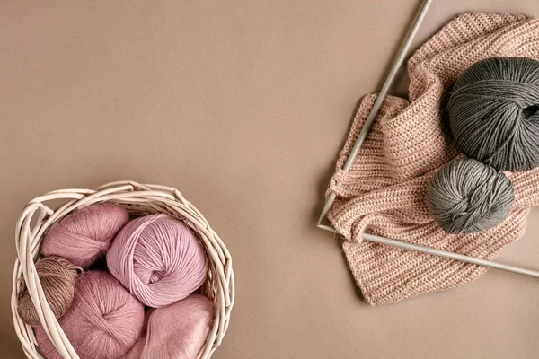 Balls of merino wool yarn, knitting on knitting needles on a beige surface. Top view