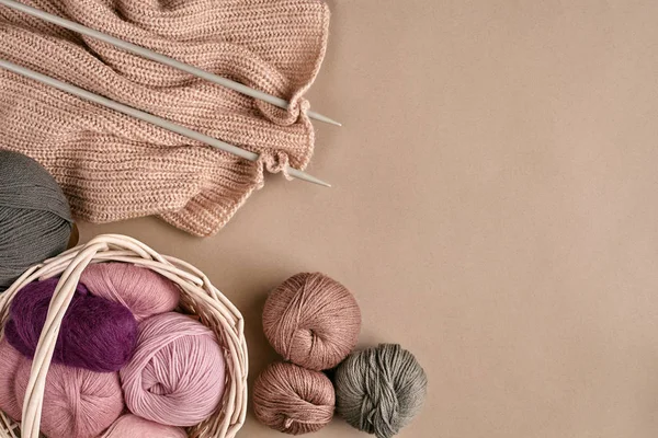Des boules de laine mérinos, tricotées sur des aiguilles à tricoter sur une surface beige. Vue du dessus — Photo