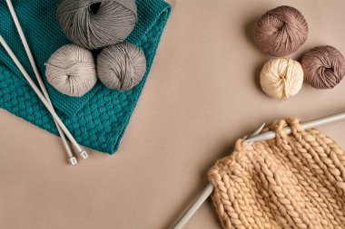 Gri ve kahverengi yün örgü ve örgü örgü iğneleri bej renkli arka plan üzerinde üzerinde. Üstten Görünüm. Kopya alanı