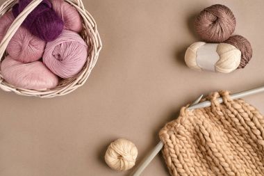 Pembe ve kahverengi yün örgü ve bej renkli arka plan üzerinde örgü iğneleri örme. Üstten Görünüm. Kopya alanı