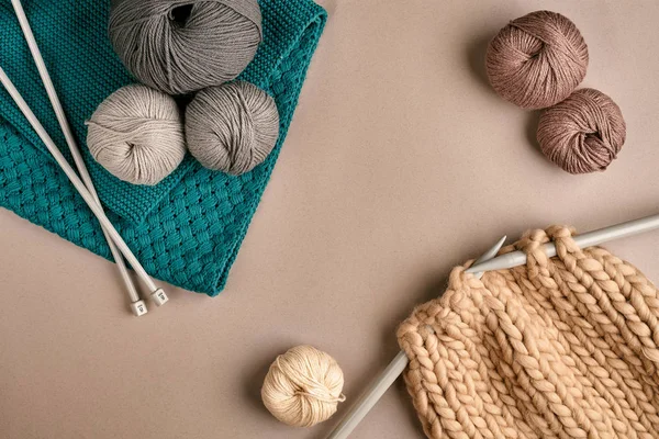 Gri ve kahverengi yün örgü ve örgü örgü iğneleri bej renkli arka plan üzerinde üzerinde. Üstten Görünüm. Kopya alanı