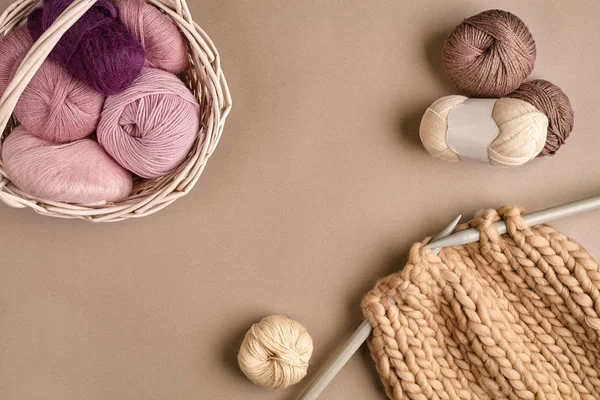 Lana per maglieria rosa e marrone e lavoro a maglia su ferri da maglia su sfondo beige. Vista dall'alto. Copia spazio — Foto Stock