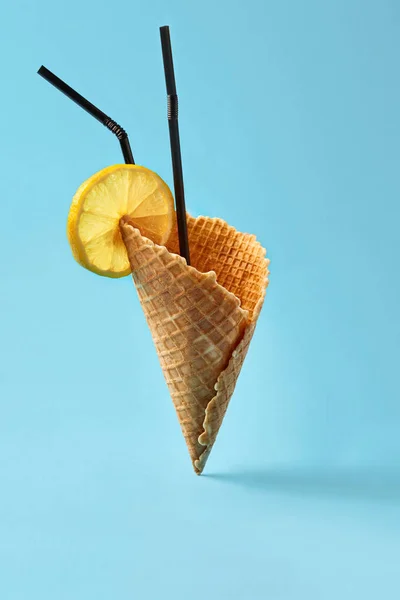 Cono de helado con pajitas negras sobre fondo azul brillante . — Foto de Stock