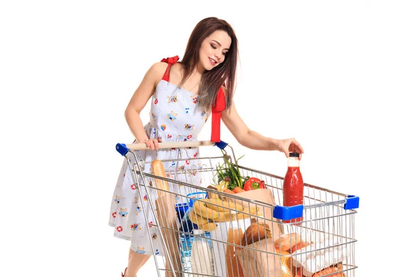 Улыбающаяся молодая женщина делает покупки в супермаркете, она кладет бутылку томатного сока в тележку — стоковое фото