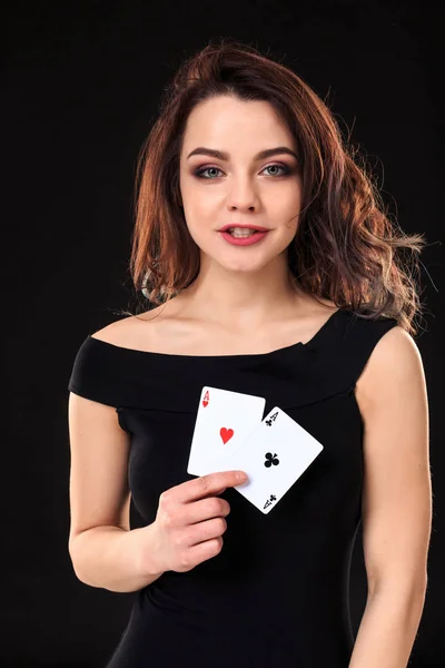 Jovem segurando cartas de jogar contra um fundo preto — Fotografia de Stock