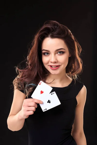 Jovem segurando cartas de jogar contra um fundo preto — Fotografia de Stock