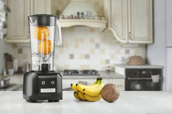 Metal food blender close-up with fresh exotic tropic fruits next to it on kitchen background with empty space. Sun flare