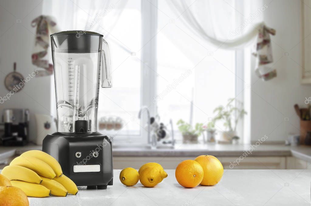 Metal food blender close-up with fresh exotic tropic fruits next to it on kitchen background with empty space