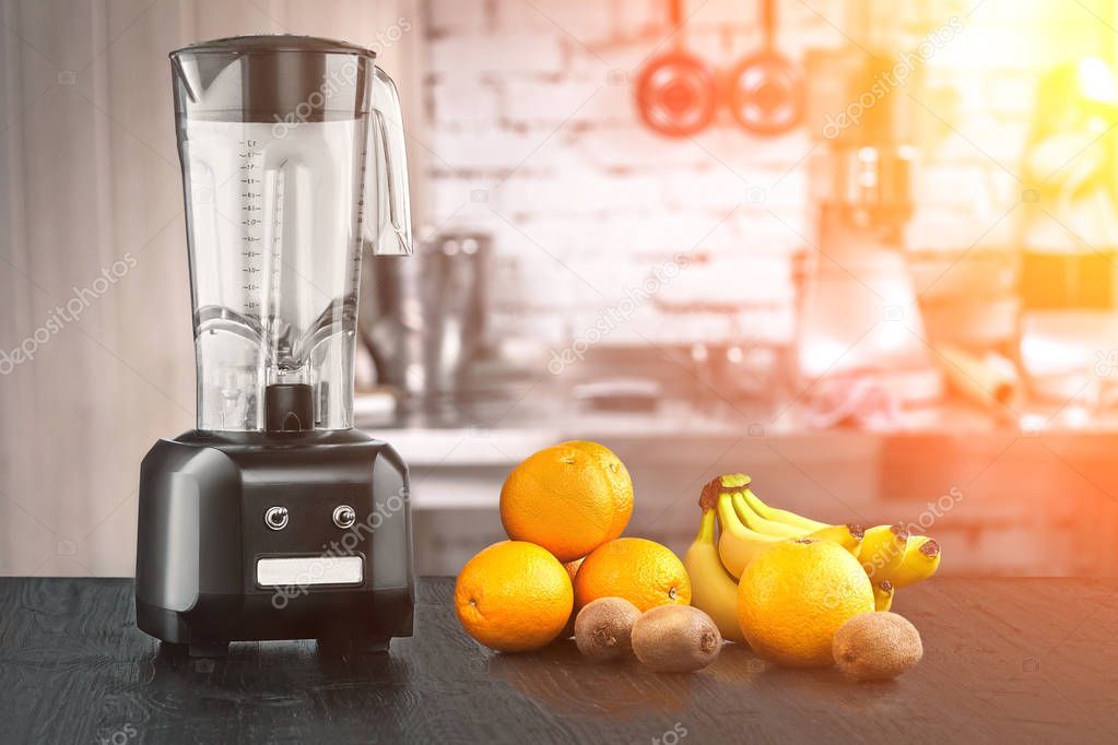 Metal food blender close-up with fresh exotic tropic fruits next to it on kitchen background with empty space. Sun flare