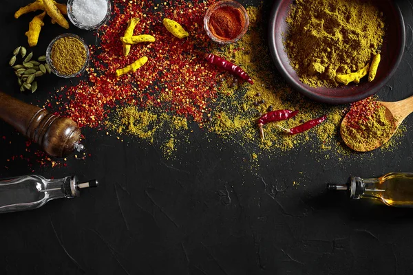 Μαγειρική χρήση φρεσκοαλεσμένο μπαχαρικά με μικρά και μεγάλα κύπελλα των μπαχαρικών σε έναν μαύρο πίνακα με διαρροή σε σκόνη στην επιφάνειά του, εναέρια προβολή με copyspace — Φωτογραφία Αρχείου