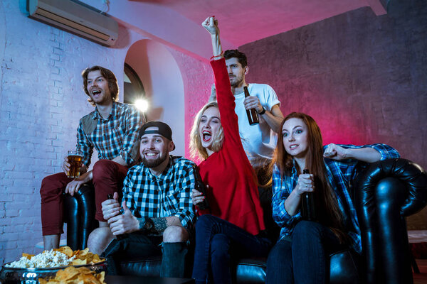 Friends watching a football match and drinking beer.