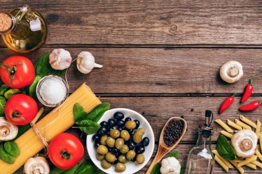 İtalyan makarna, spagetti, fesleğen, domates, zeytin ve zeytinyağı ahşap arka plan üzerinde hazırlanması için ham maddeler. Üstten Görünüm. Kopya alanı.