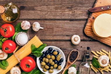 İtalyan makarna, spagetti, fesleğen, domates, zeytin ve zeytinyağı ahşap arka plan üzerinde hazırlanması için ham maddeler. Üstten Görünüm. Kopya alanı.