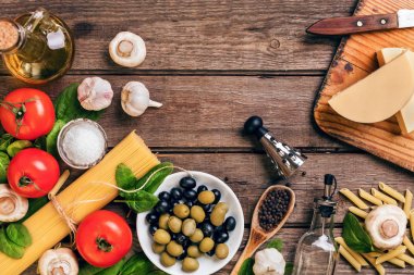 İtalyan makarna, spagetti, fesleğen, domates, zeytin ve zeytinyağı ahşap arka plan üzerinde hazırlanması için ham maddeler. Üstten Görünüm. Kopya alanı.