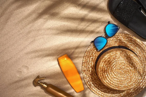 Літній фон з солом'яним капелюхом, сонцезахисними окулярами, пляшкою сонця та фліп-флоп — стокове фото