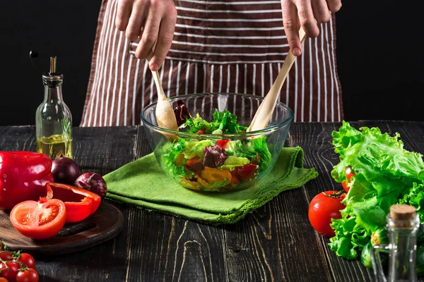 나무 테이블에 신선한 야채와 함께 샐러드를 준비 하는 남자. 맛있고 건강 한 음식을 요리 — 스톡 사진