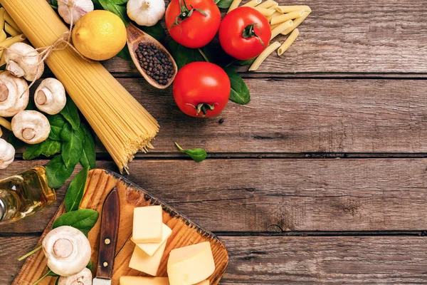 Comida italiana cocina-tomates, albahaca, pasta, aceite de oliva y queso sobre fondo de madera, vista superior, espacio para copiar . — Foto de Stock