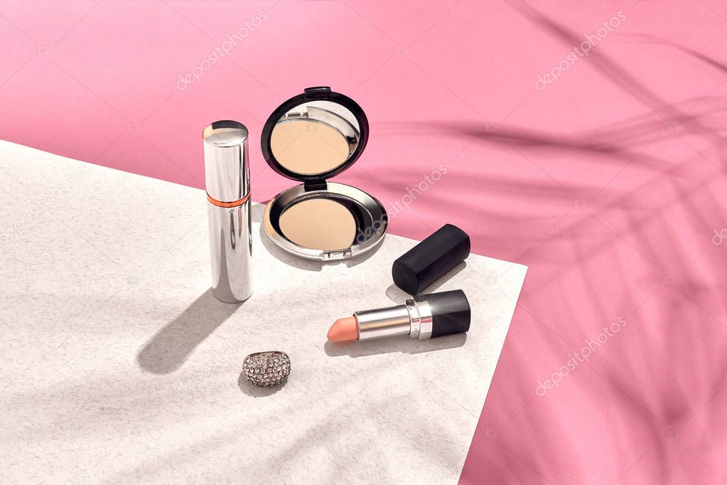 Fashionable Womens Cosmetics and Accessories. Flat Lay. Pink and white background. Shadow from a palm leaf