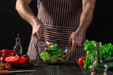 Adam ahşap bir masa üzerinde taze sebze salatası hazırlama. Yemek lezzetli ve sağlıklı yemek