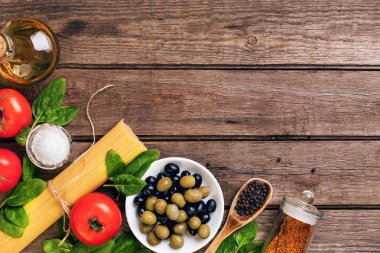 İtalyan makarna, spagetti, fesleğen, domates, zeytin ve zeytinyağı ahşap arka plan üzerinde hazırlanması için ham maddeler. Üstten Görünüm. Kopya alanı.