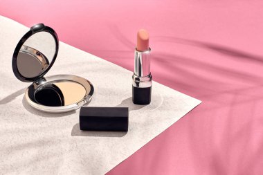 Şık kadın kozmetik ve aksesuarları. Düz yatıyordu. Pembe ve beyaz arka plan. Bir palmiye yaprak gölge