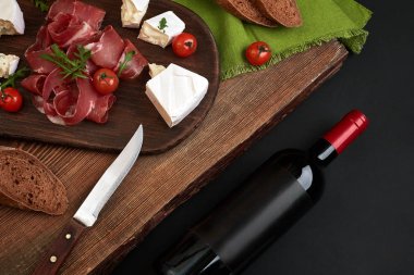 Peynir ve kopya alanı siyah zemin üzerine ahşap tahta üzerinde geleneksel sosis şarap şişesi