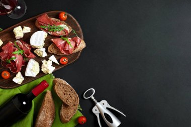 Şarap şişesi peynir ve kopya alanı siyah zemin üzerine ahşap tahta üzerinde geleneksel sosis. Natürmort. Üstten görünüm. Düz yatıyordu