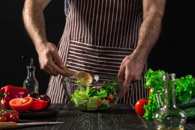 Adam ahşap bir masa üzerinde taze sebze salatası hazırlama. Yemek lezzetli ve sağlıklı yemek