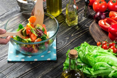 Adam ahşap bir masa üzerinde taze sebze salatası hazırlama. Yemek lezzetli ve sağlıklı yemek. Yakın çekim