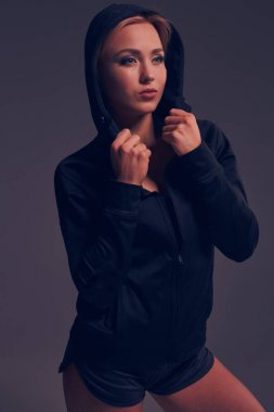 Stüdyoda siyah kapüşon, spor iç çamaşırı ve küçük siyah şort ince seksi şekilde baştan çıkarıcı sportif kızla güzel poz