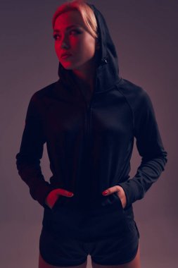 Stüdyoda siyah kapüşon, spor iç çamaşırı ve küçük siyah şort ince seksi şekilde baştan çıkarıcı sportif kızla güzel poz