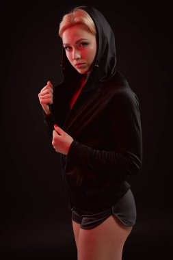 Stüdyoda siyah kapüşon, spor iç çamaşırı ve küçük siyah şort ince seksi şekilde baştan çıkarıcı sportif kızla güzel poz