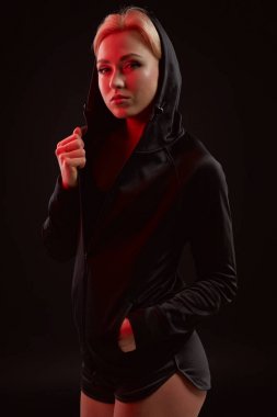 Stüdyoda siyah kapüşon, spor iç çamaşırı ve küçük siyah şort ince seksi şekilde baştan çıkarıcı sportif kızla güzel poz