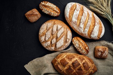 Fırın ekmek üreticileri - altın rustik huysuz somun ekmek ve siyah kara tahta zemin üzerine buns.