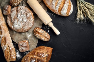 Fırın ekmek üreticileri - altın rustik huysuz somun ekmek ve siyah kara tahta zemin üzerine buns.