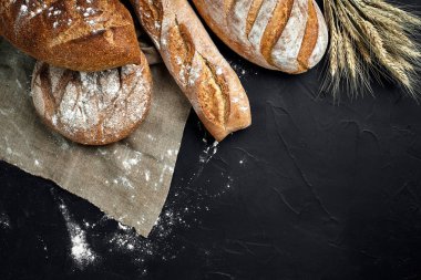 Fırın ekmek üreticileri - altın rustik huysuz somun ekmek ve siyah kara tahta zemin üzerine buns.