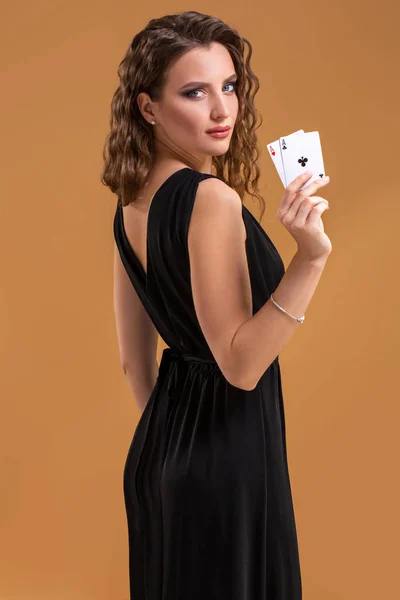 Bella donna dai capelli castani che tiene due assi come segno per il gioco del poker, il gioco d'azzardo e il casinò — Foto Stock