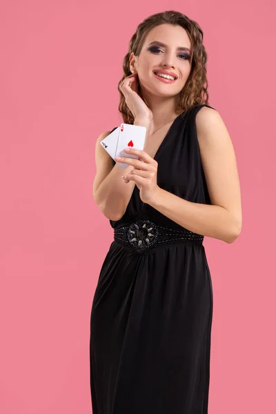 Junge Frau mit zwei Assen in der Hand vor rosa Hintergrund — Stockfoto