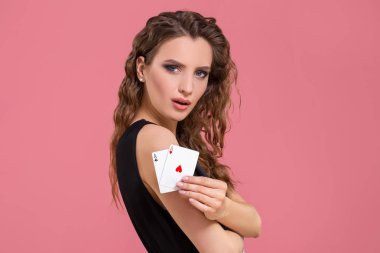 Young woman holding two aces in hand against on pink background clipart