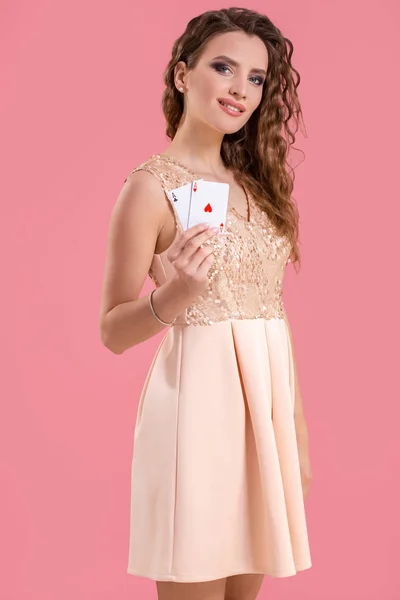 Молодая красивая женщина держит выигрышную комбинацию покерных карт на розовом фоне. Два туза — стоковое фото
