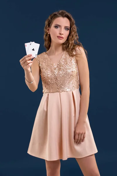 Νεαρή όμορφη γυναίκα, κρατώντας το νικητήριο συνδυασμό από χαρτιά του πόκερ σε σκούρο μπλε φόντο. Δύο άσους — Φωτογραφία Αρχείου