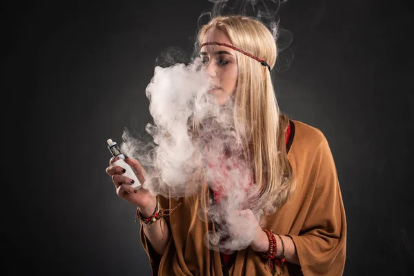 Retrato de jovem hipster sexy fumando menina vaping. A mulher está vestida com o estilo de um boho. Conceito de vapor. Vaping e-cigarro . — Fotografia de Stock