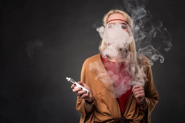 Portrait of sexy young hipster smoking vaping girl. The woman is dressed in the style of a boho. Vapor concept. Vaping e-Cigarette. — Stock Photo, Image