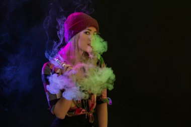 Vaping kız. Genç hipster kadın vape e-cig siyah arka plan üzerine. Hip-hop tarzı. Stüdyo vurdu