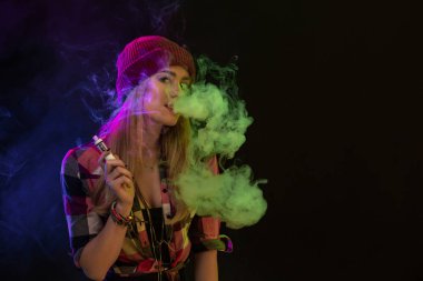 Vaping kız. Genç hipster kadın vape e-cig siyah arka plan üzerine. Hip-hop tarzı. Stüdyo vurdu