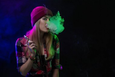 Vaping kız. Genç hipster kadın vape e-cig siyah arka plan üzerine. Hip-hop tarzı. Stüdyo vurdu