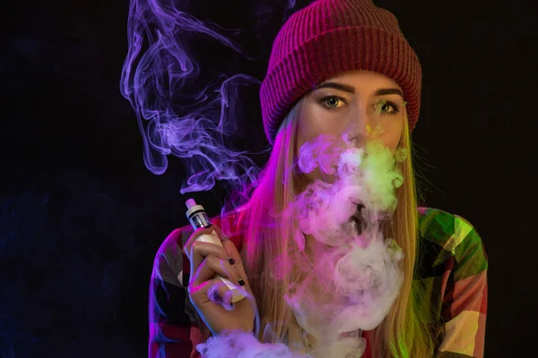 Vaping 女孩年轻的时髦女人 vape 在工作室的黑色背景上的电子香烟。嘻哈风格。特写. — 图库照片