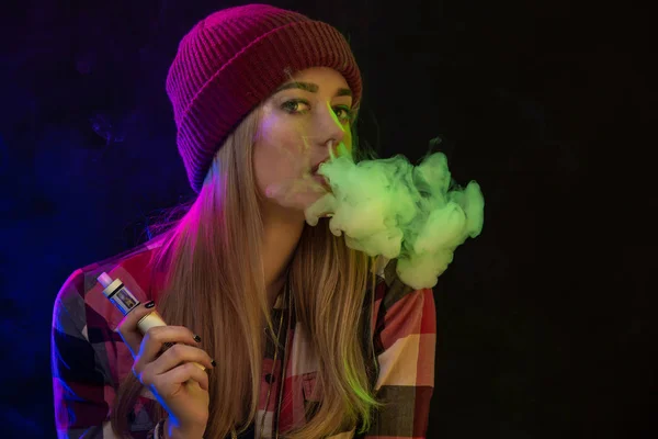 Vaping 女孩年轻的时髦女人 vape 在工作室的黑色背景上的电子香烟。嘻哈风格。特写. — 图库照片