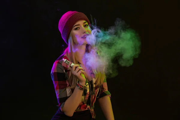 Rapariga vacilante. Mulher jovem hipster vape e-cig em fundo preto. Estilo hip-hop. Estúdio — Fotografia de Stock